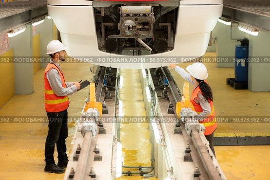 Male and female engineers work together in an electric repair station. Inspect head of electric trains that come in for repairs in the skytrain repair station. Стоковое фото, агентство Ingram Publishing / Фотобанк Лори
