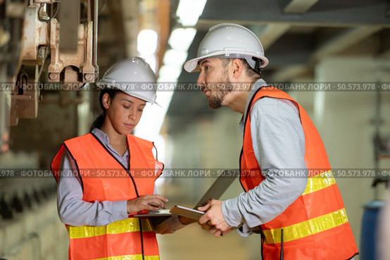 Male and female engineers work together in an electric repair station. Inspecting the undercarriage of electric train that are being repaired at the garage. Стоковое фото, агентство Ingram Publishing / Фотобанк Лори