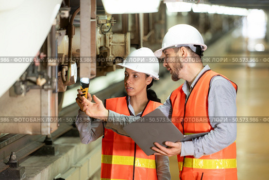 Male and female engineers work together in an electric repair station. Inspecting the undercarriage of electric train that are being repaired at the garage. Стоковое фото, агентство Ingram Publishing / Фотобанк Лори
