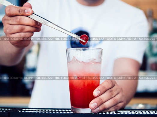 male bartender decorating drink with cherry. Стоковое фото, агентство Ingram Publishing / Фотобанк Лори