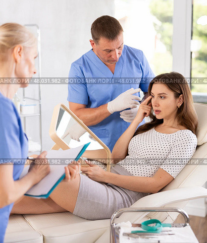 Male beautician, together with a nurse, examines face of an young woman and plans facelift procedures. Стоковое фото, фотограф Яков Филимонов / Фотобанк Лори
