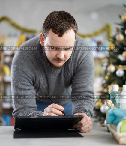 Male businessperson with tablet, plans to replenish restock stores inventory on Christmas Eve. Стоковое фото, фотограф Яков Филимонов / Фотобанк Лори