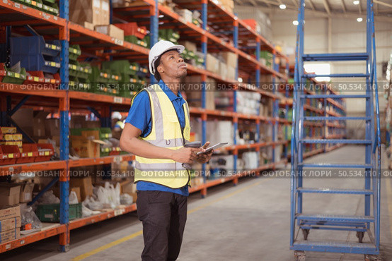 Male clerk using digital tablet while standing on stairs in warehouse to inspect goods. Стоковое фото, агентство Ingram Publishing / Фотобанк Лори
