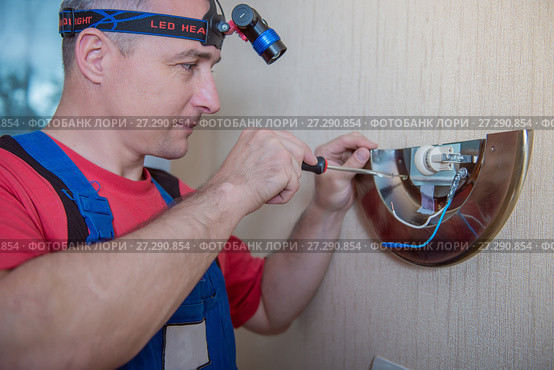 Male electrician connects the lamp on the wall. Стоковое фото, фотограф Наталья Давыдова / Фотобанк Лори