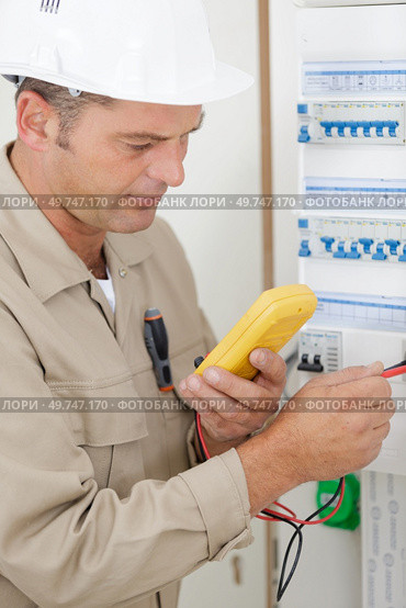 male electrician using multimeter on fusebox. Стоковое фото, агентство Ingram Publishing / Фотобанк Лори