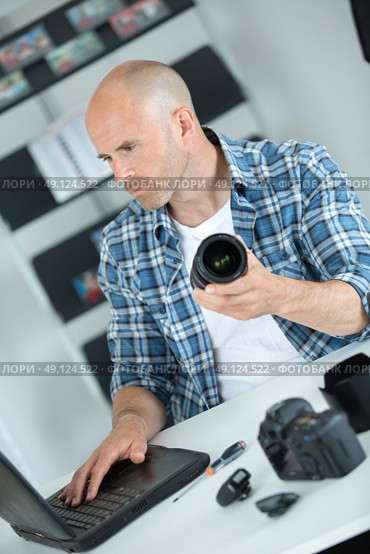 male middle-aged photographer sitting on the desk with laptop. Стоковое фото, агентство Ingram Publishing / Фотобанк Лори