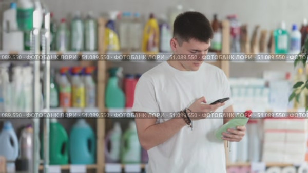 Male shopper checks a QR code on a dishwashing sponge label in a supermarket. Стоковое видео, видеограф Яков Филимонов / Фотобанк Лори