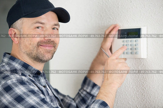 male technician programming electronic keypad. Стоковое фото, агентство Ingram Publishing / Фотобанк Лори