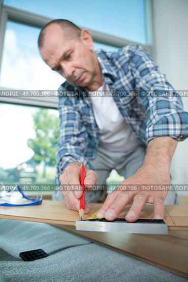 male worker lying parquet floor board- laminate flooring. Стоковое фото, агентство Ingram Publishing / Фотобанк Лори