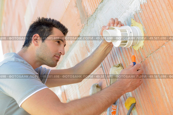 male worker repairing ventilation hatch. Стоковое фото, агентство Ingram Publishing / Фотобанк Лори