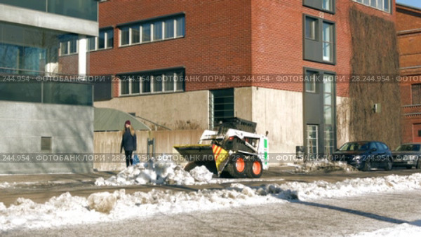 Маленький погрузчик "Bobcat" собирает снег на тротуаре. Турку, Финляндия (2018 год). Редакционное видео, видеограф Виктор Карасев / Фотобанк Лори