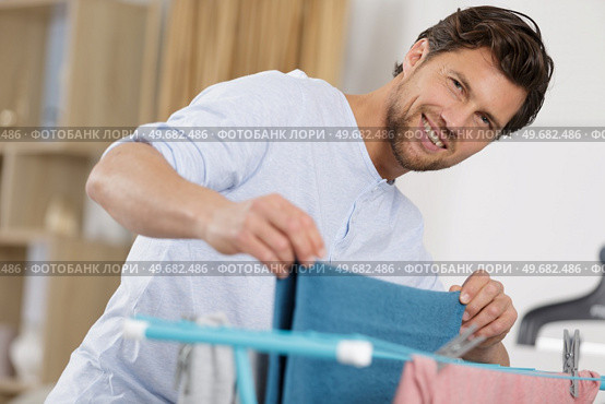 man airing laundry indoors. Стоковое фото, агентство Ingram Publishing / Фотобанк Лори
