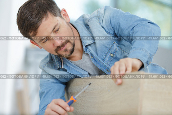 man assembling wooden flatpack furniture. Стоковое фото, агентство Ingram Publishing / Фотобанк Лори