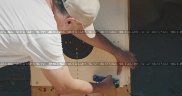 Man attaches a clean paper target at an outdoor shooting range. Стоковое видео, видеограф Igor Tichonow / Фотобанк Лори