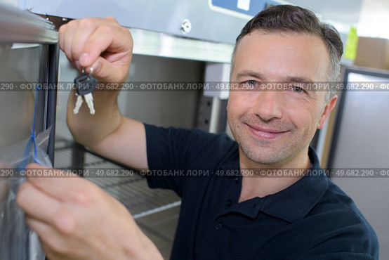 Man by refridgerator holding up set of keys. Стоковое фото, агентство Ingram Publishing / Фотобанк Лори