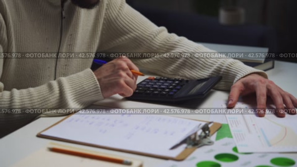 Man Calculating Budget With Calculator and Paperwork at Home Office Desk. Стоковое видео, видеограф Сергей Толмачёв / Фотобанк Лори