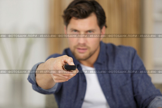 man changing channels while watching tv at home. Стоковое фото, агентство Ingram Publishing / Фотобанк Лори