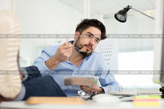 man changing tv channel with remote control while eating sandwich. Стоковое фото, агентство Ingram Publishing / Фотобанк Лори