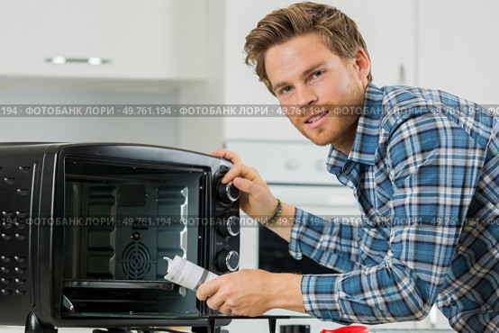 man cleaning up after replacing the filter in a microwave. Стоковое фото, агентство Ingram Publishing / Фотобанк Лори