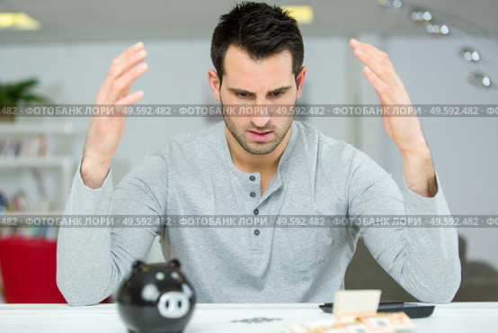 man confuse with his piggy bank calculations. Стоковое фото, агентство Ingram Publishing / Фотобанк Лори