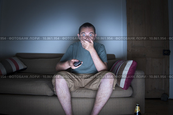 man covering mouth watching tv. Стоковое фото, фотограф Lee Avison / PantherMedia / Фотобанк Лори