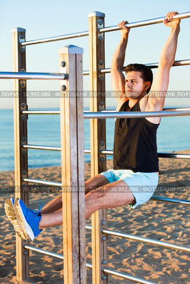 Man doing workout on beach holding L-sit on wall bars. Стоковое фото, фотограф Яков Филимонов / Фотобанк Лори
