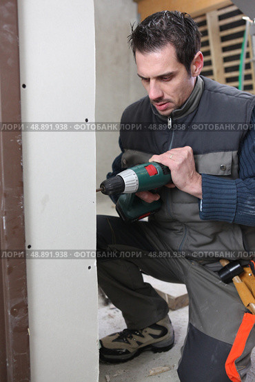 Man drilling an interior wall. Стоковое фото, агентство Ingram Publishing / Фотобанк Лори