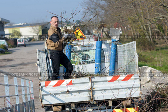 man emptying litter from truck trailer at the community landfill. Редакционное фото, агентство Ingram Publishing / Фотобанк Лори