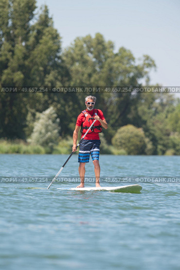 man enjoying a ride on the lake with paddleboard. Стоковое фото, агентство Ingram Publishing / Фотобанк Лори