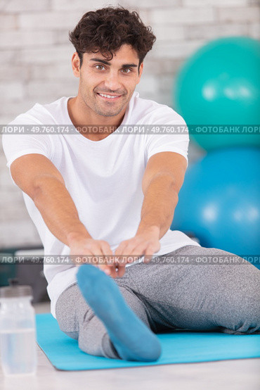 man exercising and stretching towards his toes. Стоковое фото, агентство Ingram Publishing / Фотобанк Лори