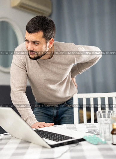 Man experiencing severe back pain after working long hours on laptop. Стоковое фото, фотограф Яков Филимонов / Фотобанк Лори