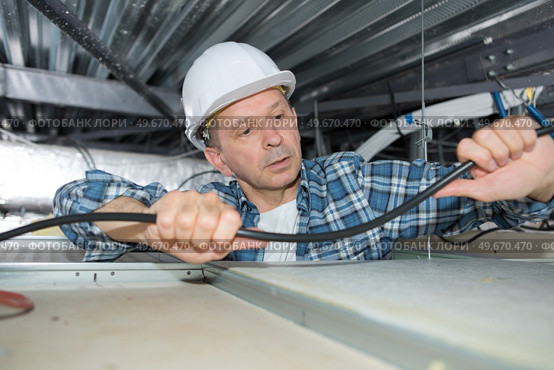 man fixing wires on the ceiling. Стоковое фото, агентство Ingram Publishing / Фотобанк Лори