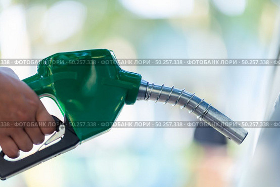 Man Handle pumping gasoline fuel nozzle to refuel. Vehicle fueling facility at petrol station. White car at gas station being filled with fuel. Transportation and ownership concept. Стоковое фото, агентство Ingram Publishing / Фотобанк Лори