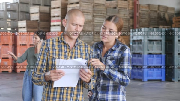 Man having conversation with young woman about documentation in warehouse. Those female colleague standing behind. Стоковое видео, видеограф Яков Филимонов / Фотобанк Лори