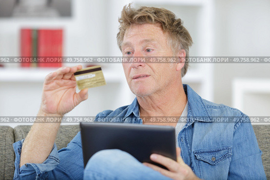 man holds tablet and credit card in his hands. Стоковое фото, агентство Ingram Publishing / Фотобанк Лори