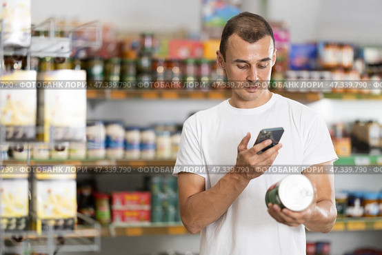 Man in supermarket scan QR code on jar canned food. Стоковое фото, фотограф Яков Филимонов / Фотобанк Лори