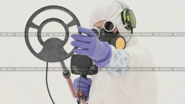Man in white chemical protection suit holds metal detector. Стоковое видео, видеограф Aleksey Kidisyuk / Фотобанк Лори