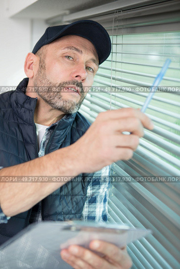 man is inspecting the window blinds. Стоковое фото, агентство Ingram Publishing / Фотобанк Лори
