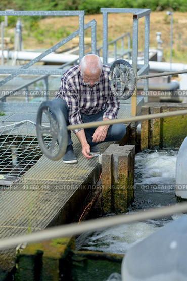 Man kneeling on lock gates. Стоковое фото, агентство Ingram Publishing / Фотобанк Лори