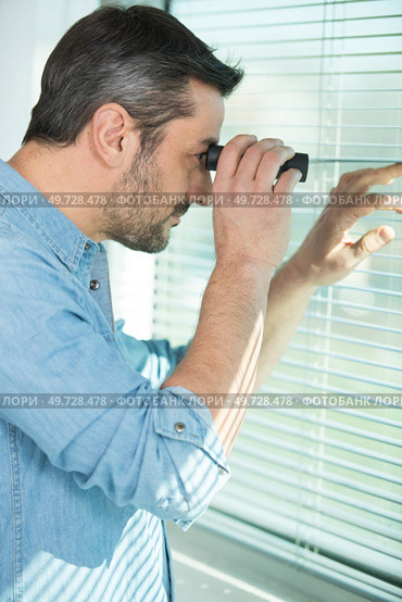 man looking through binoculars at window blind. Стоковое фото, агентство Ingram Publishing / Фотобанк Лори