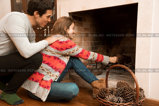 man looking young woman placing pinecone fireplace. Стоковое фото, агентство Ingram Publishing / Фотобанк Лори