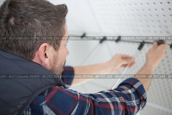 man mounts metal racks on the wall. Стоковое фото, агентство Ingram Publishing / Фотобанк Лори