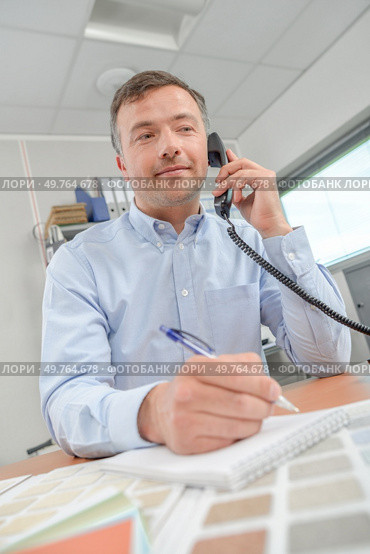 Man on telephone, colour charts in front of him. Стоковое фото, агентство Ingram Publishing / Фотобанк Лори