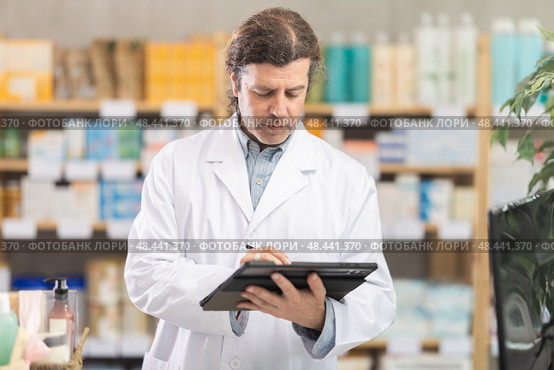 Man pharmacist makes restock, uses electronic carrier tablet of information. Стоковое фото, фотограф Яков Филимонов / Фотобанк Лори
