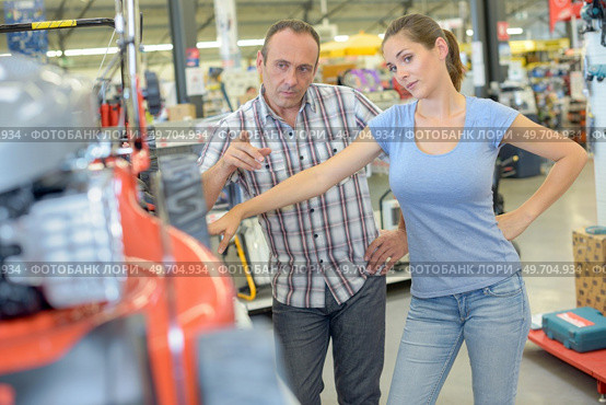 Man pointing to mower, woman looking skeptical. Стоковое фото, агентство Ingram Publishing / Фотобанк Лори