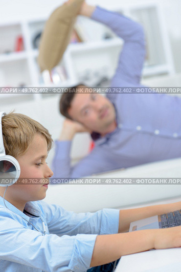 Man poised to throw cushion at young boy on computer. Стоковое фото, агентство Ingram Publishing / Фотобанк Лори