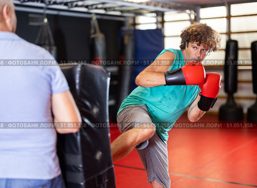 Man practicing foot strikes on kick shield with trainer. Стоковое фото, фотограф Яков Филимонов / Фотобанк Лори