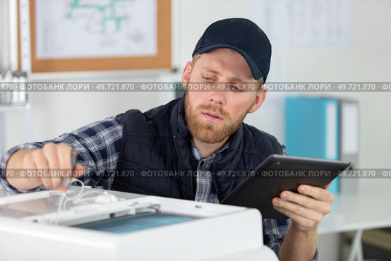 man repairing photocopier using tablet. Стоковое фото, агентство Ingram Publishing / Фотобанк Лори