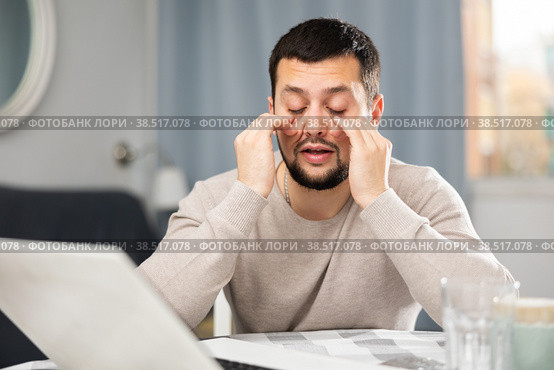 Man rubs tired eyes with his hands after a long work at laptop at home. Стоковое фото, фотограф Яков Филимонов / Фотобанк Лори