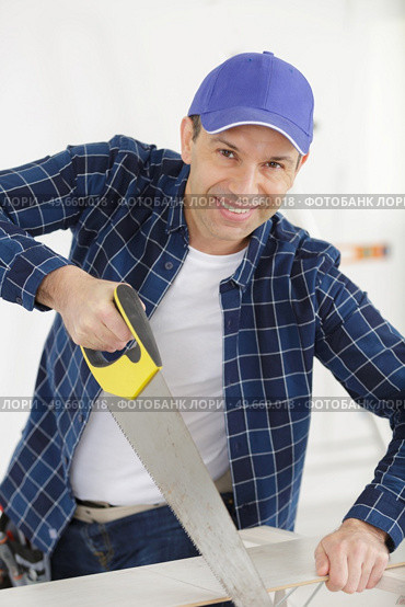 man sawing a board with a hacksaw. Стоковое фото, агентство Ingram Publishing / Фотобанк Лори